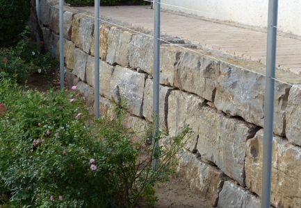 Mauer an Pflanzenstreifen und Zaun