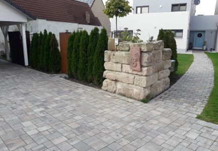 Natürlicher Sichtschutz aus kleinen Bäumen und Natursteinmauer