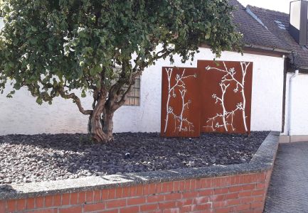 Baum auf Schotterecke neben Sichtschutz im Rostlook