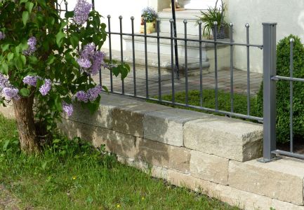Mauer mit Zaun an Grünstreifen